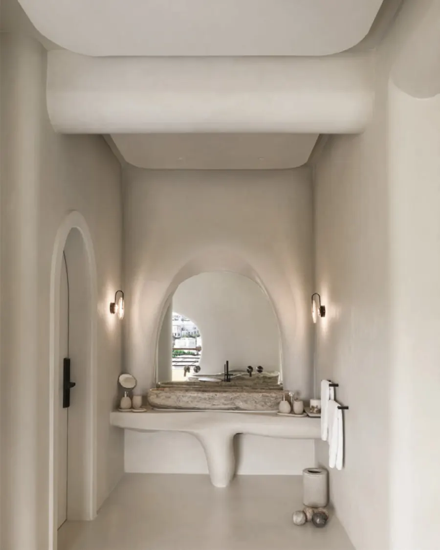 Sculpted washbasin vanity in a white arched bathroom